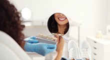 Woman’s smile reflected in handheld mirror above shade guide