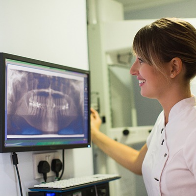 dental assistant looking at X-ray after advanced dental implant procedure in McKinney