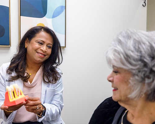 Female dentist showing model of teeth to patient