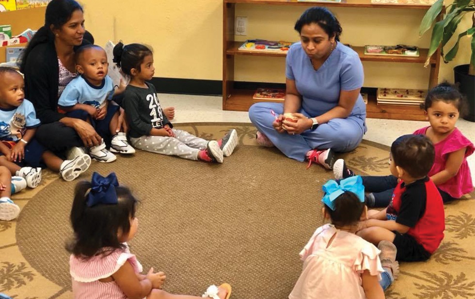 Dr Parmar sitting in circle with kids