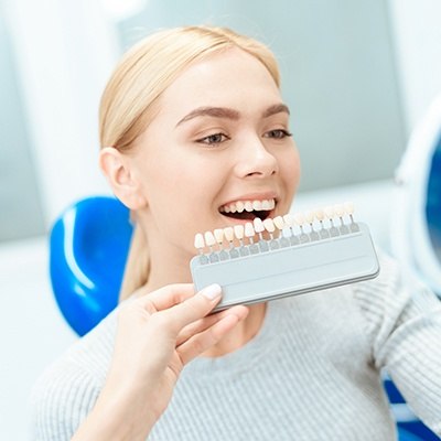 Woman's smile compared with tooth color chart