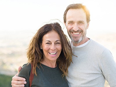 A middle-aged couple smiling while posing outside after seeing their Delta Dental in-network dentist in McKinney