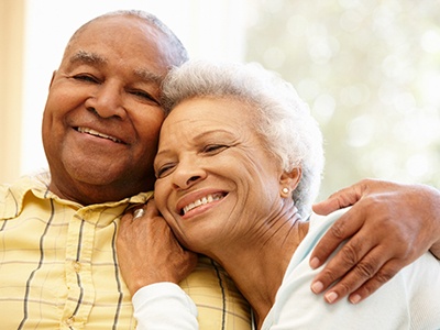 An older man and woman hugging and sitting together, expressing their happiness