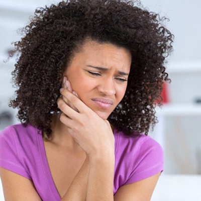 woman holding side of her face in pain