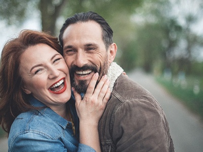 A middle-aged couple laughing and smiling after seeing their GEHA dentist in McKinney