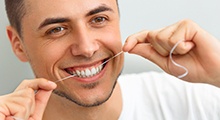 man flossing his dental implants McKinney