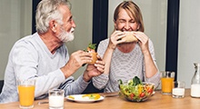 Older couple eating lunch with dental implants in McKinney