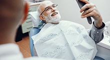 Older man smiling with an implant dentist in McKinney