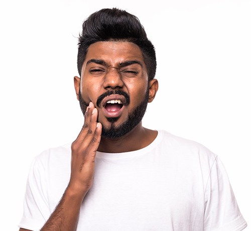 Man holding cheek in dental pain