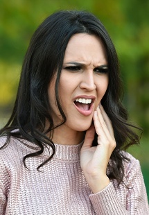 woman holding her jaw in pain