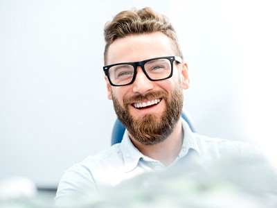 man with glasses in dental chair smiling 