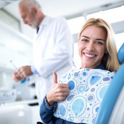 woman giving thumbs up in dental chair