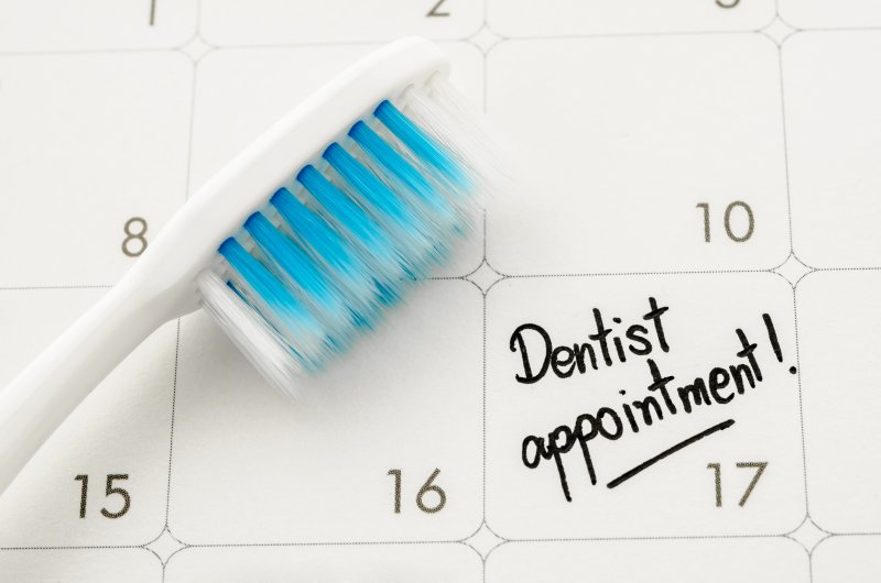 an image of a toothbrush lying on a calendar with “Dentist Appointment” written on one of the dates