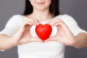 person holding a red love heart in their hands 