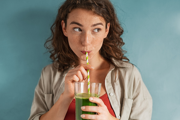 woman drinking green juice looking off to side