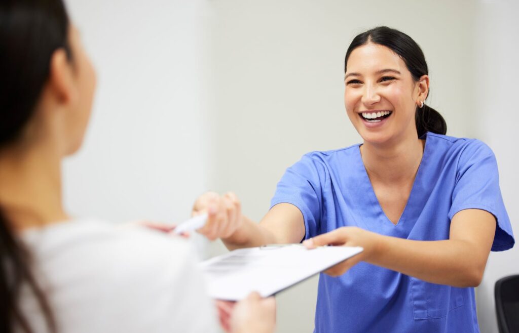 A dentist handing a patient a form to fill out.