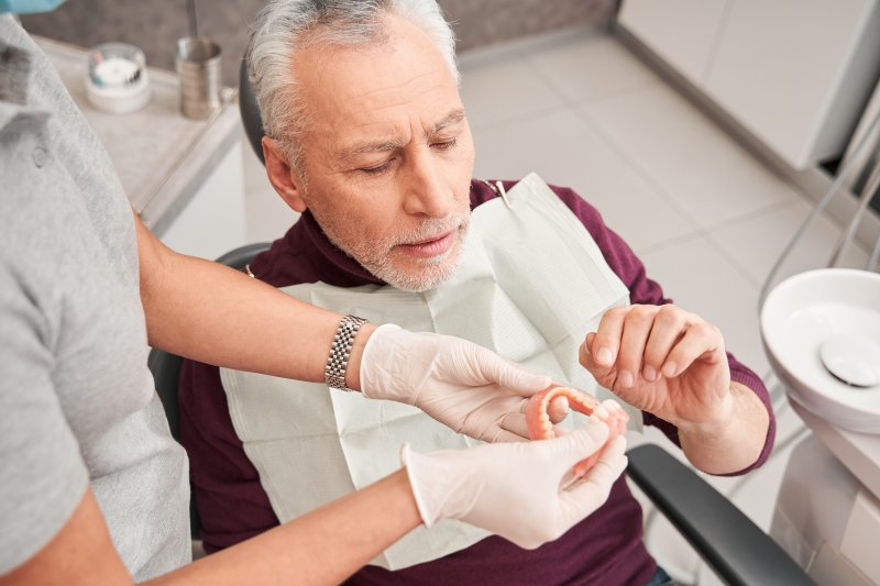 A dentist showing dentures to her patient